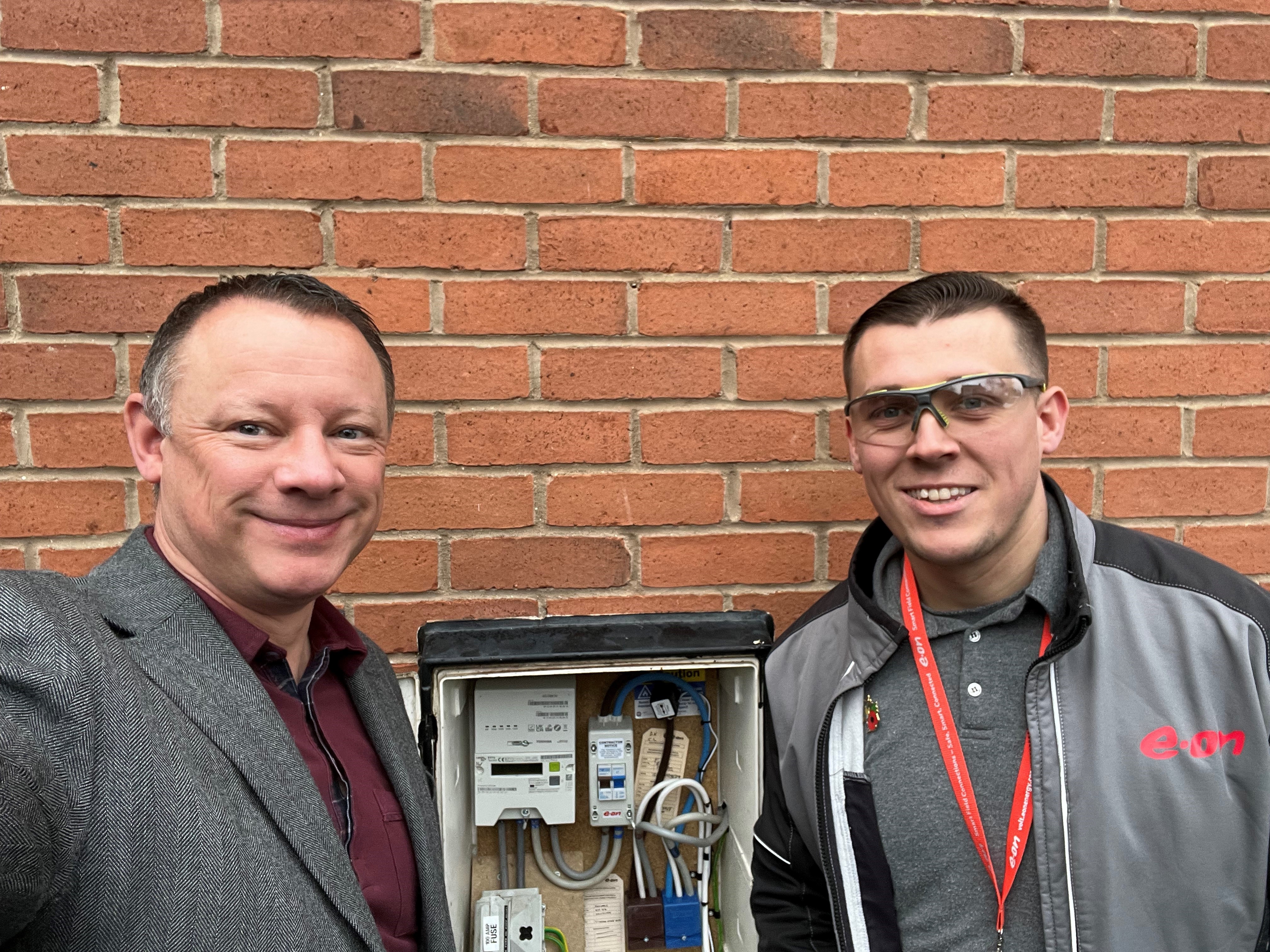 Two people standing in front of one of the first 4G Communication Hubs to be installed in Britain